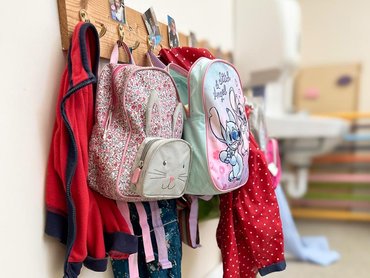 a coat rack with children's coats and backpacks