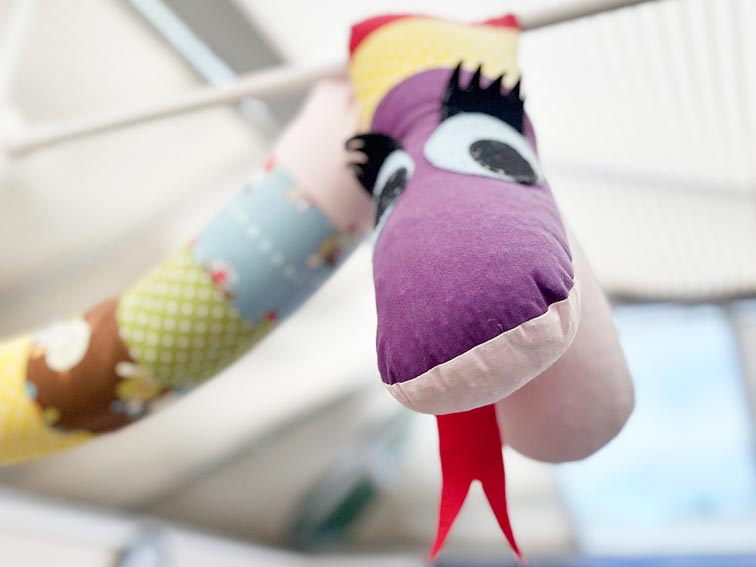 a close up of a colourful plushie snake hanging from the ceiling