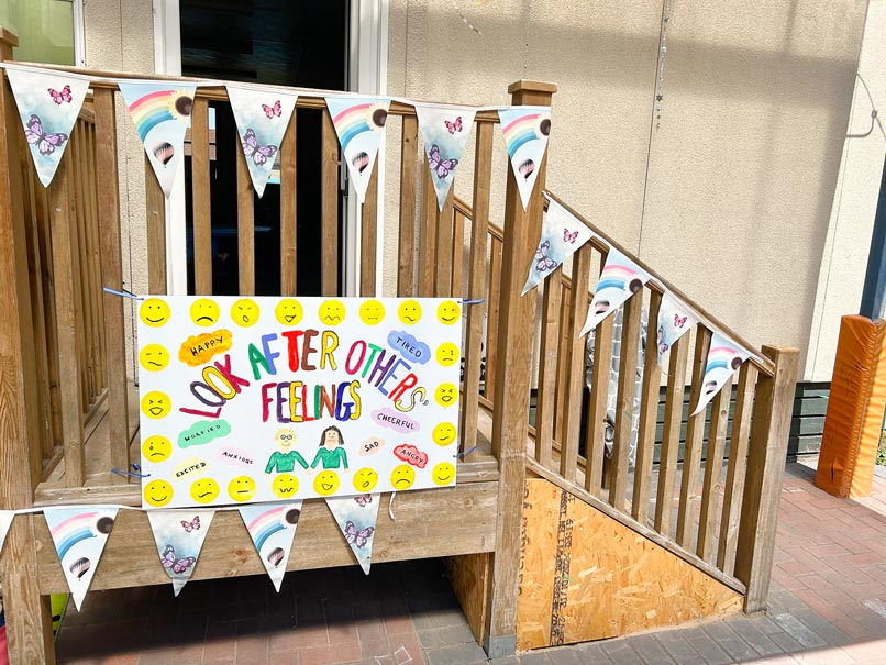 wooden steps leading to a building with bunting and a hand painted sign saying 'look after others feelings'