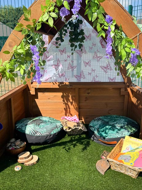 an arch structure outdoors with round cushions and children's books underneath