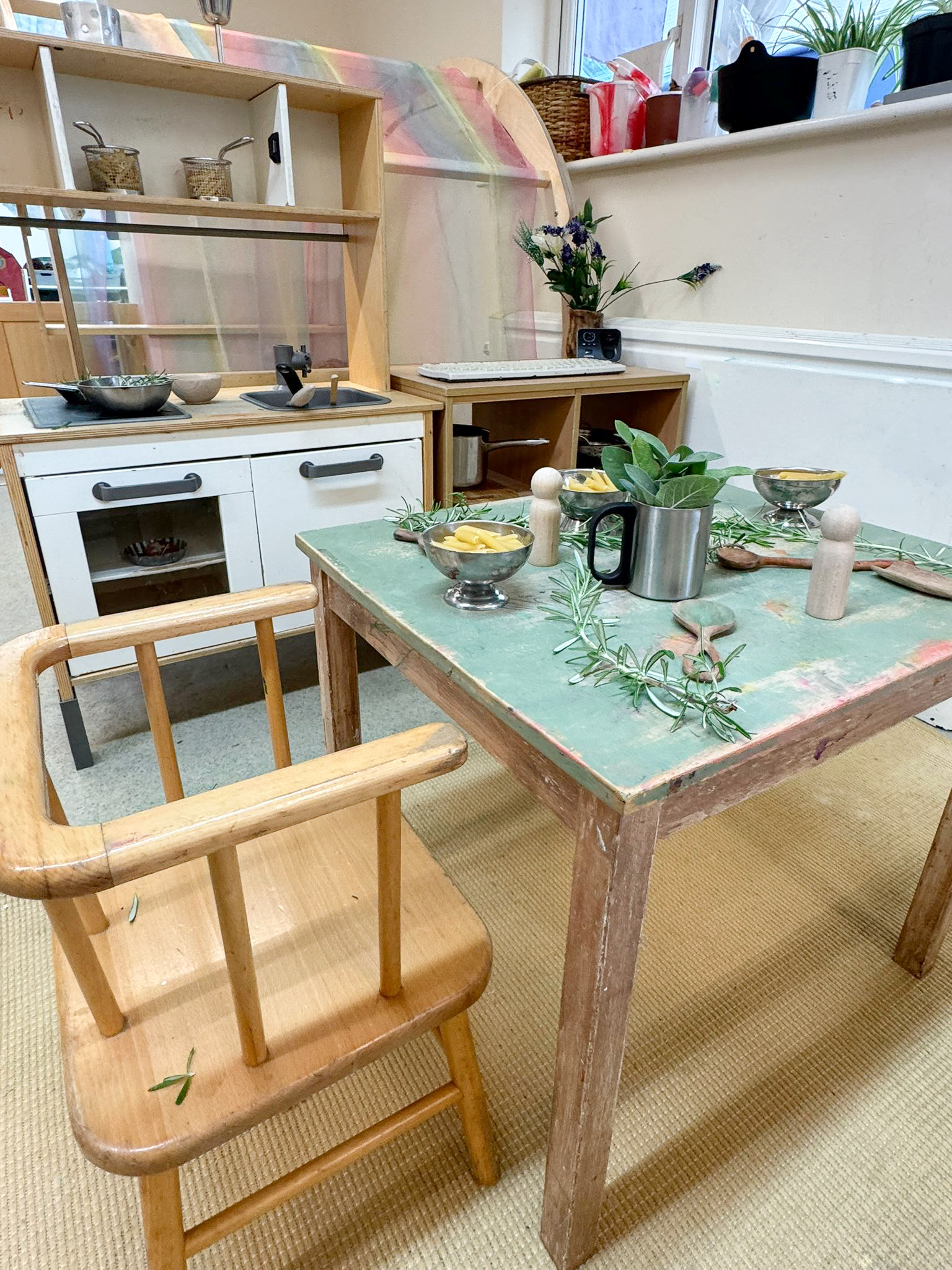 a childrens play kitchen area with dried pasta and herbs set up
