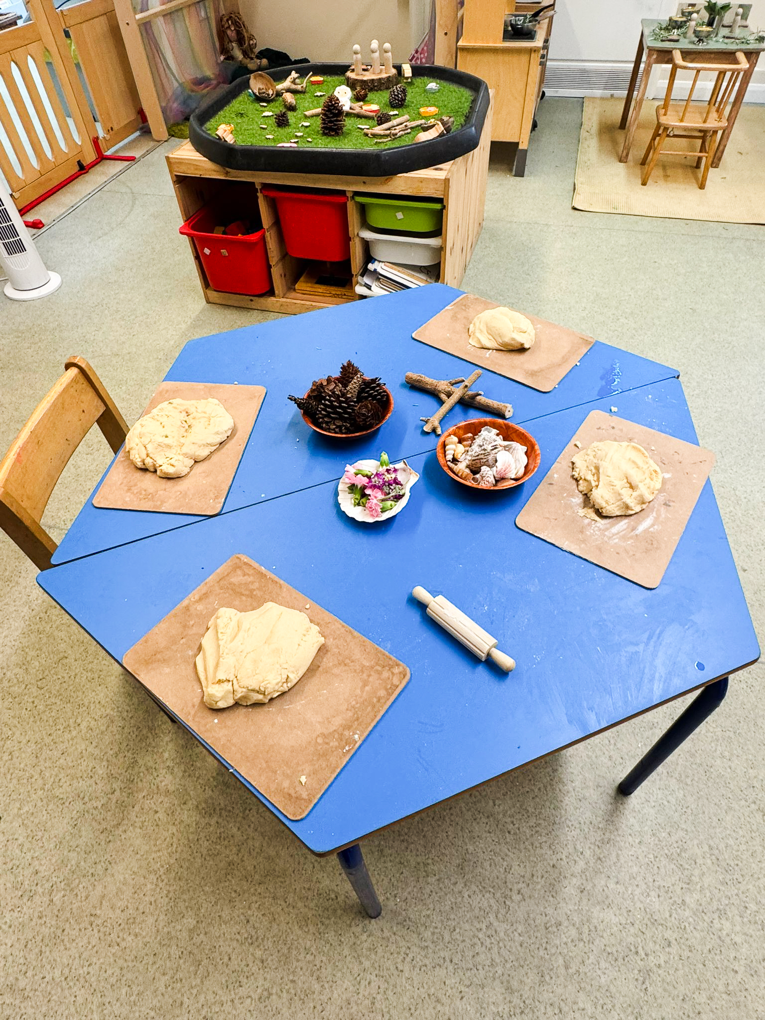 a childrens table in a nursery set up with dough and natural materials