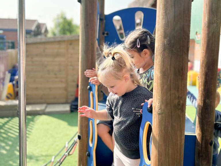 two young girls playing outside on a playset