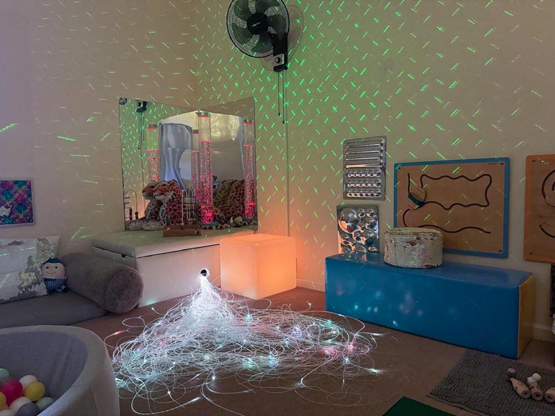 a children's sensory room with colourful lights, a ball pit and soft pillows