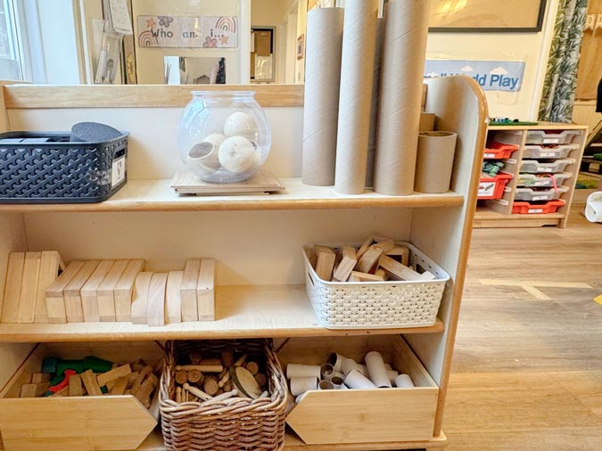 a shelf with children's toys including wooden blocks, cardboard rolls and sticks