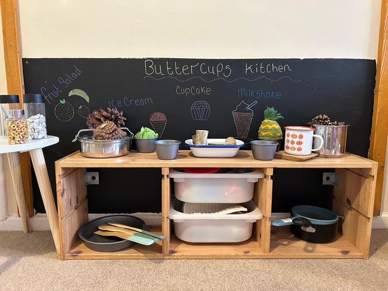 a children's play area with kitchen utensils and natural materials including pinecones